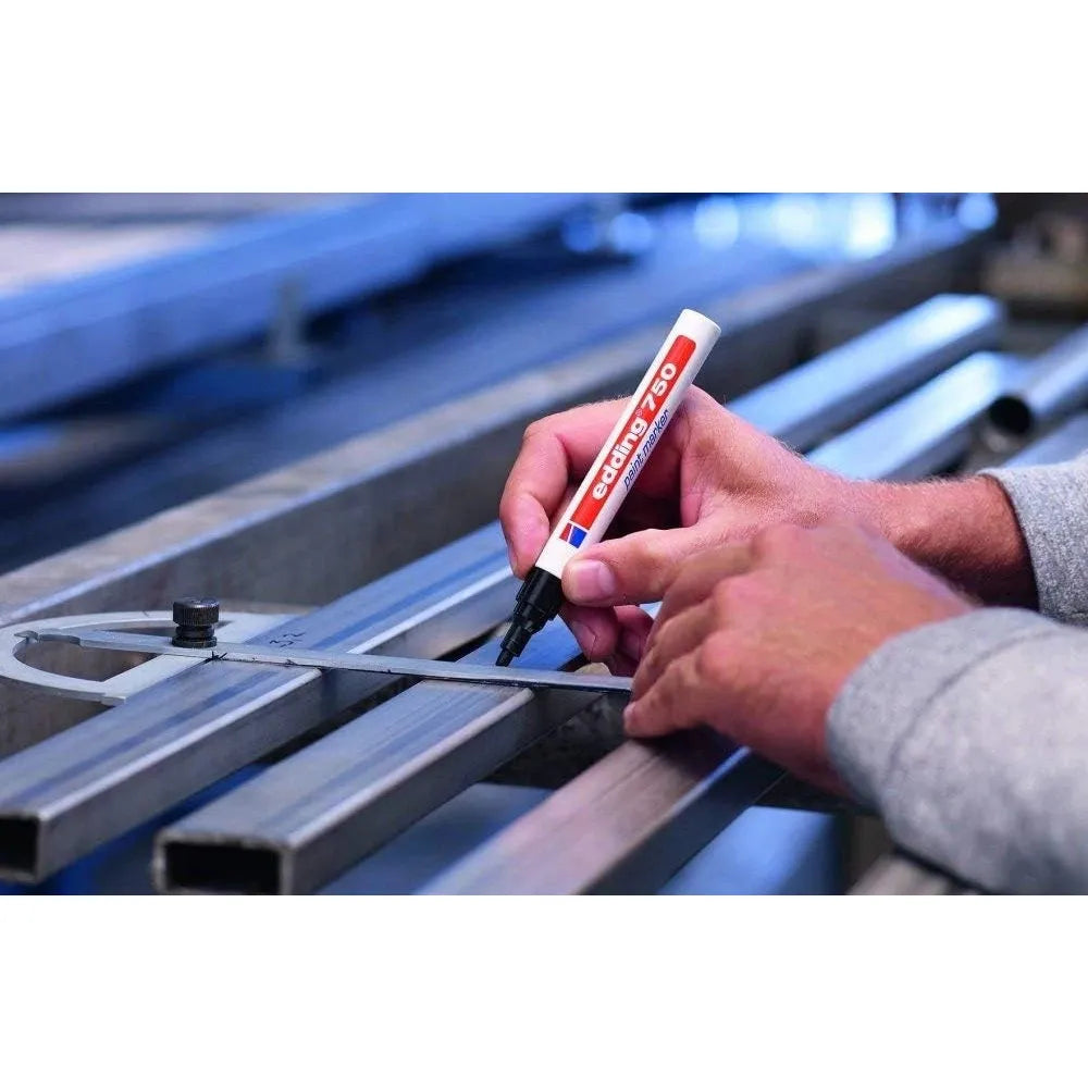 Person marking metal pipes with a marker in an industrial setting